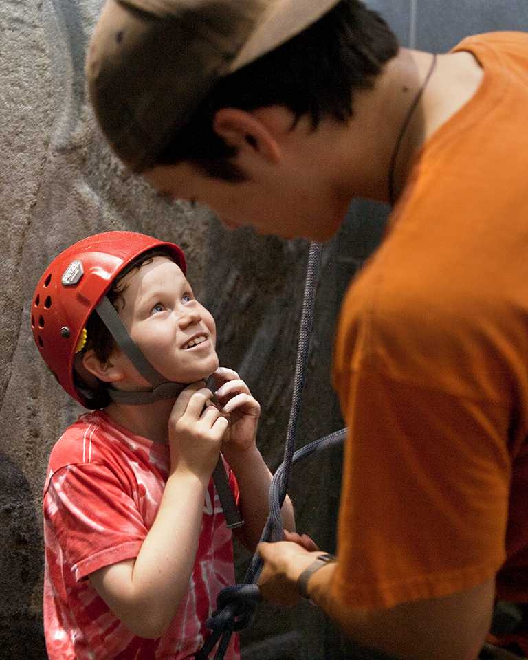 Smiling boy getting harnessed in for rock climbing