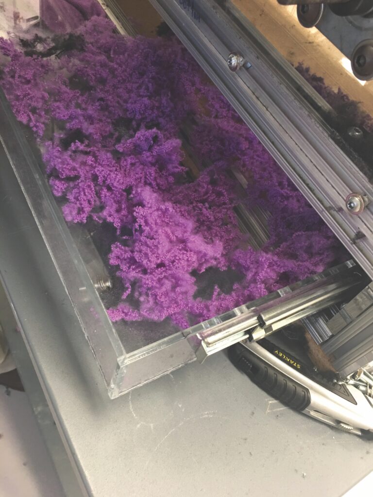 Shreds of purple material that have been processed by the Fiberizer machine.