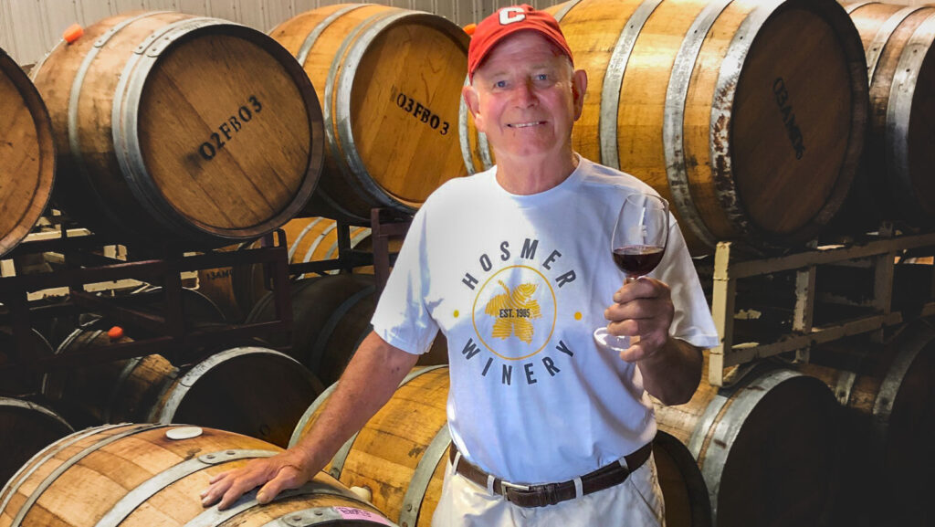 Cameron Hosmer ’76, pictured with a glass of wine and wine barrels, founded Hosmer Winery, located on the eastern shore of Cayuga Lake in Ovid, NY, with his wife, Maren, in 1985
