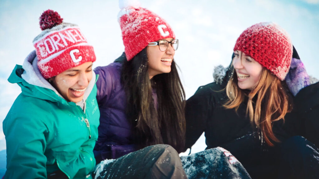 Three students in red hats enjoy a fun moment in the snowy outdoors