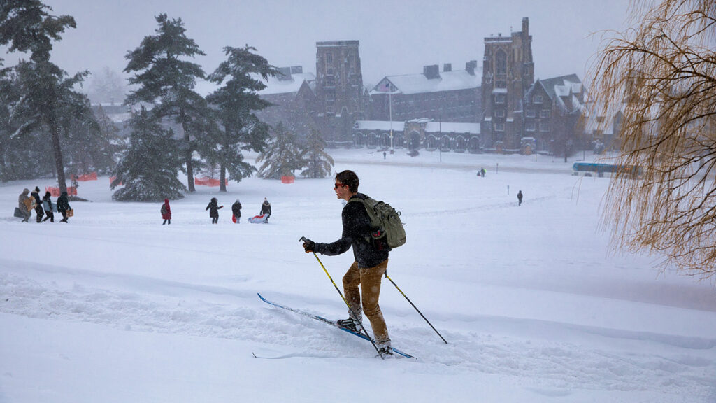 students navigate their way across Libe Slope, including one on cross-country skis, as snow blankets campus