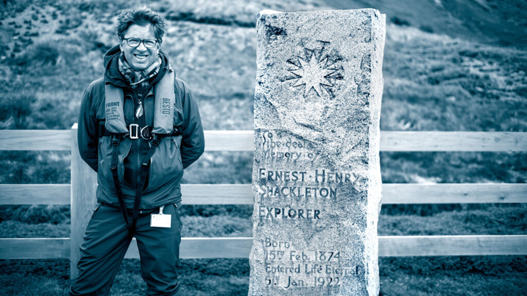 Tyler Nordgren poses next to a stone monument in Antarctica