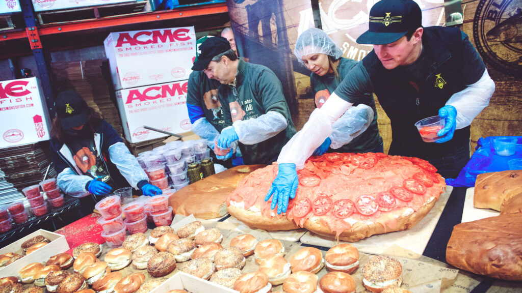 Dan Pace of Zucker's bagels and Emily Caslow Gindi and Adam Caslow of Acme Smoked Fish during the 2018 attempt to set a world record for the largest bagel-and-lox sandwich ever made