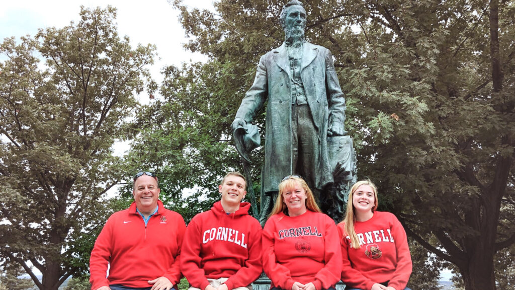 a family of four dressed in red in front of a statue