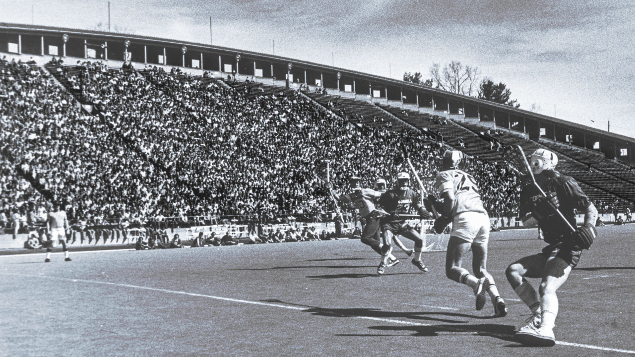Lacrosse players on the field at Cornell in front of a packed crowed in the mid-1970s