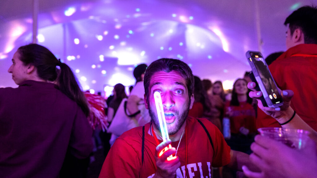 A glow stick lights the face of one Reunion attendee at the tents on the Arts Quad Saturday night