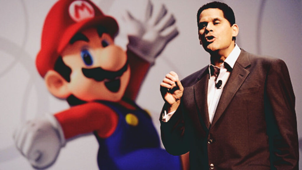 Reggie Fils-Aimé speaking in front of an image of Mario