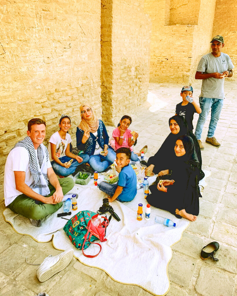 Barnard eating lunch outdoors with a family in Samarra, Iraq