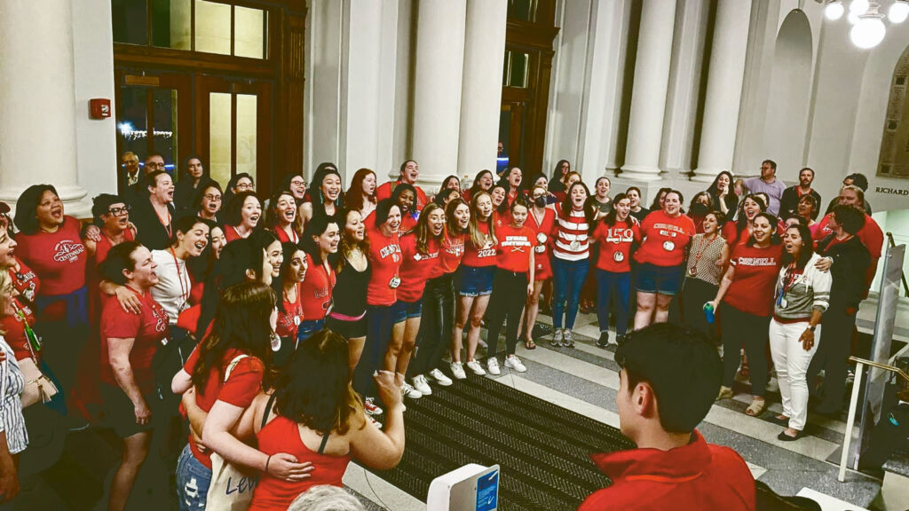 A group of women in red T-shirts singing in a chorus