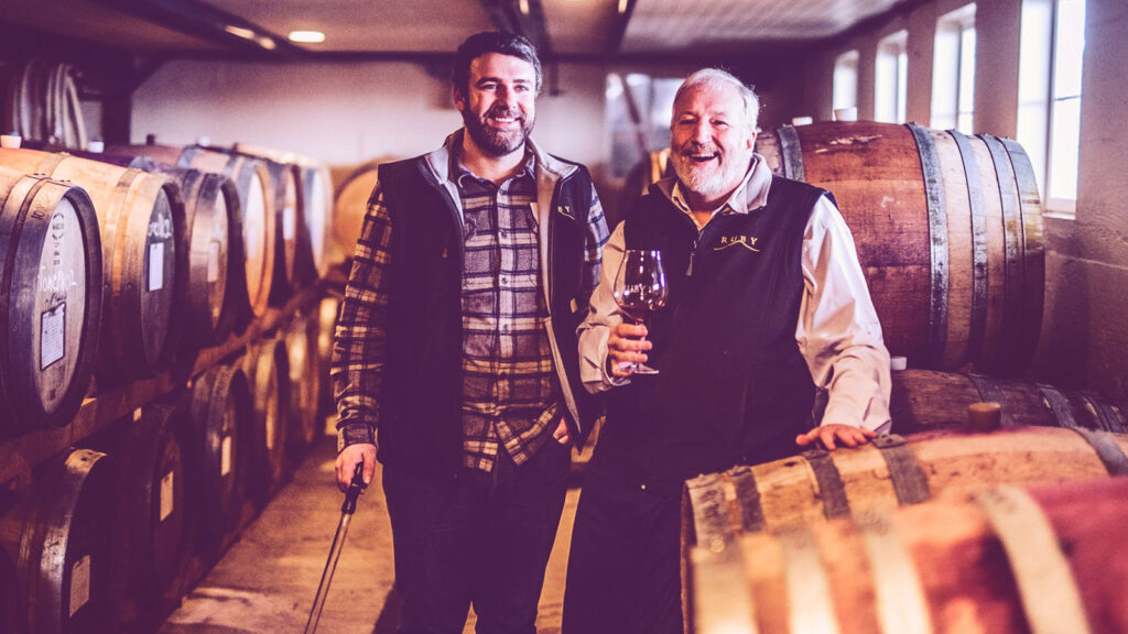 Two men surrounded by wine barrels