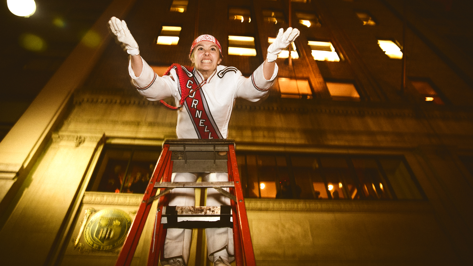 Drum major directs Big Red Marching Band from ladder outside Cornell Club in New York City