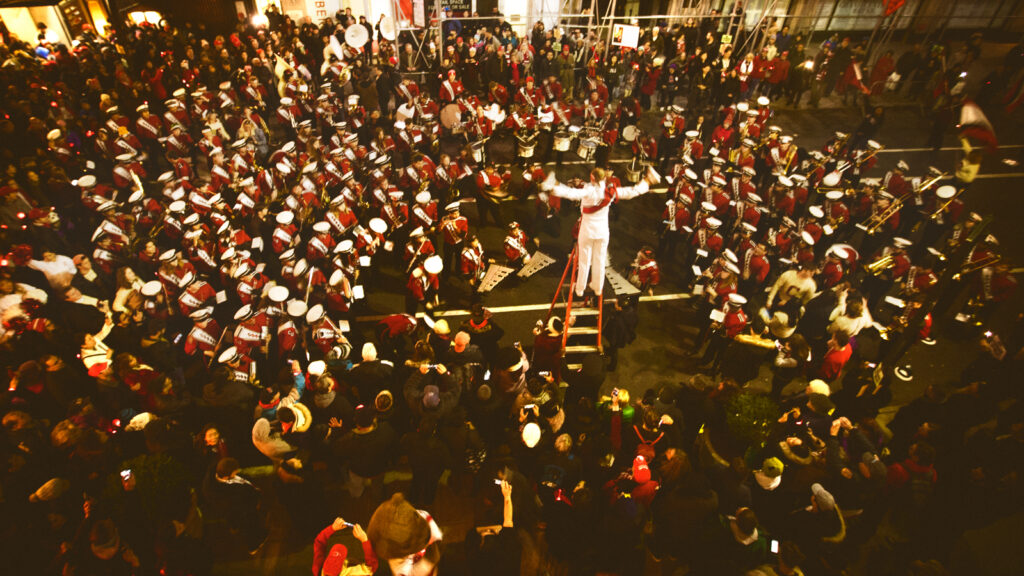 The Big Red Band leader stands on a ladder while directing the band at the Sy Katz '31 Parade