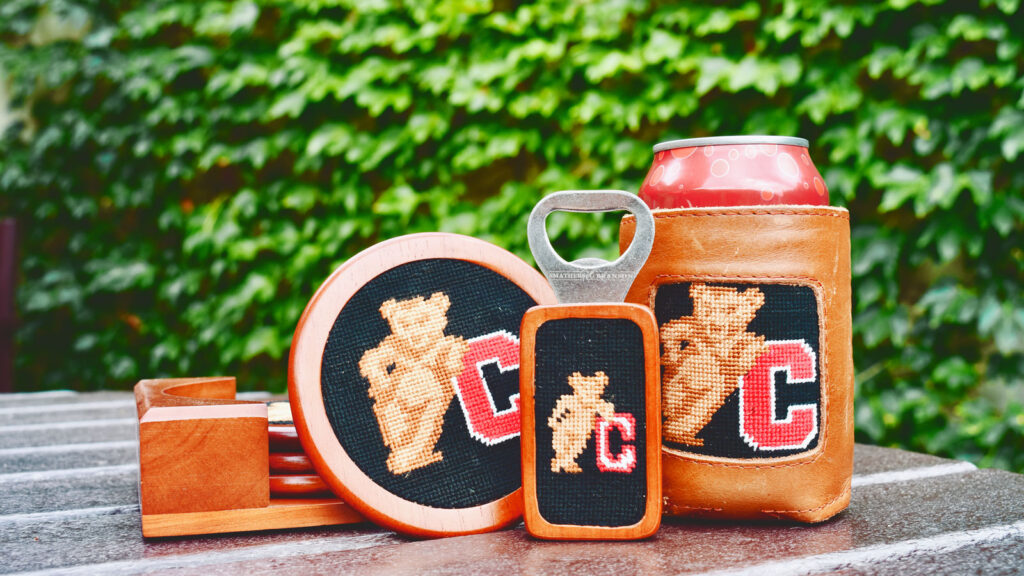 Needlepointed Cornell coaster, a bottle opener, and a can koozie