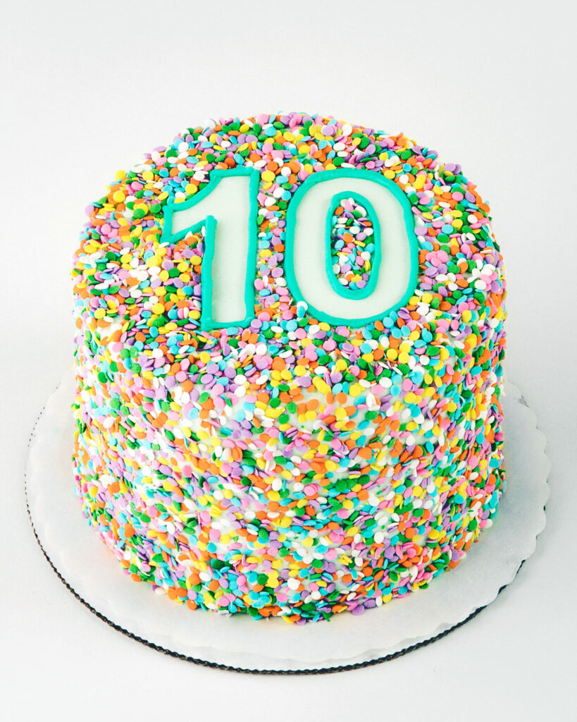 A birthday cake decorated with multicolored confetti and the number 10