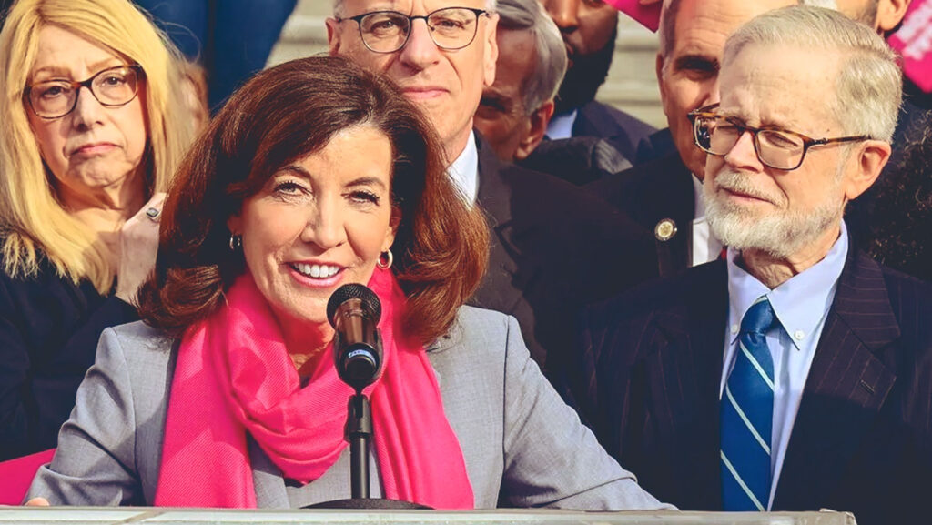 NY Governor Kathy Hochul speaking at a rally for abortion rights, with Assemblyman Richard Gottfried standing next to her.