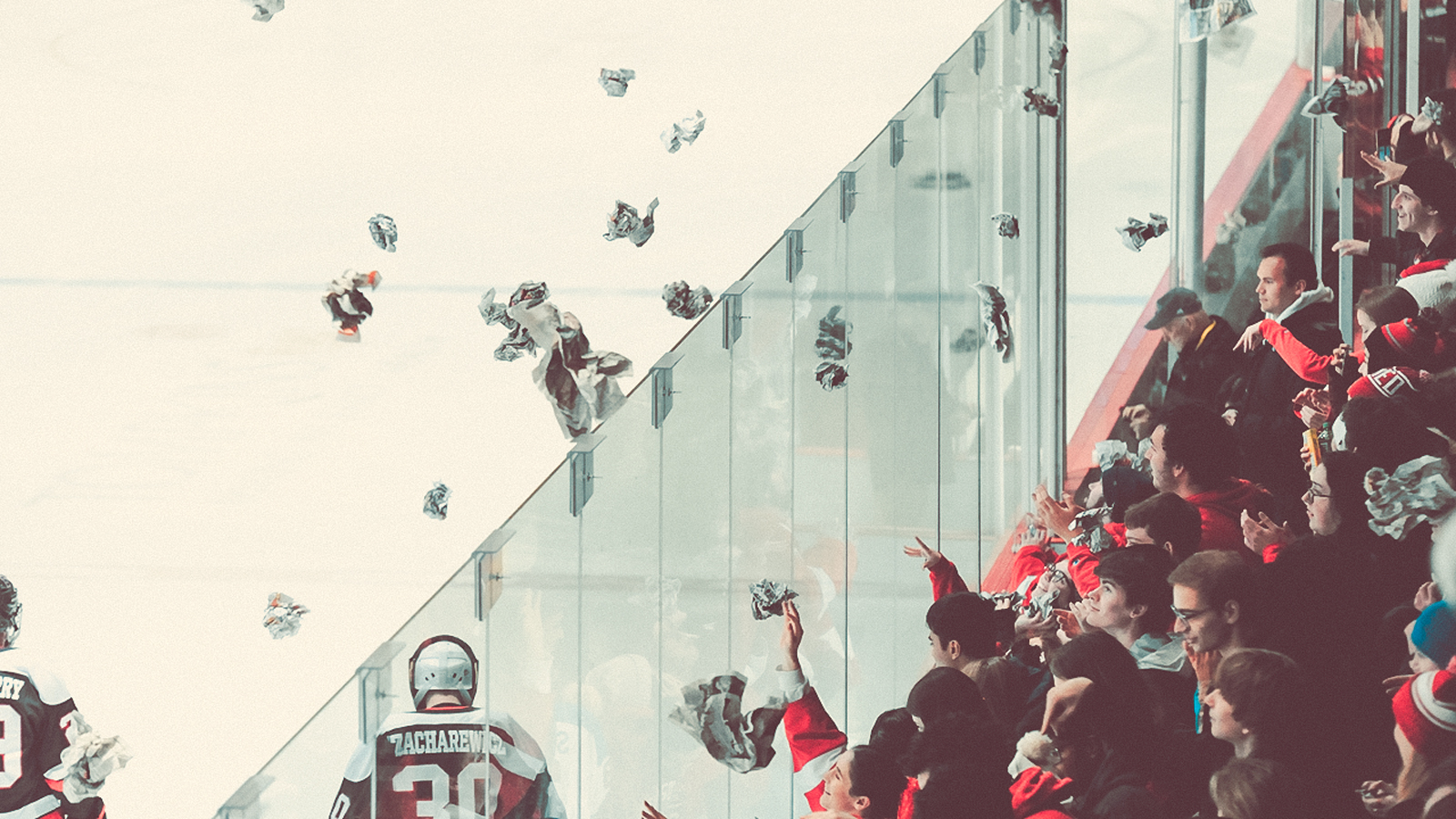 A Cornell University hockey game where fans are throwing crumpled pieces of newspaper onto the ice.