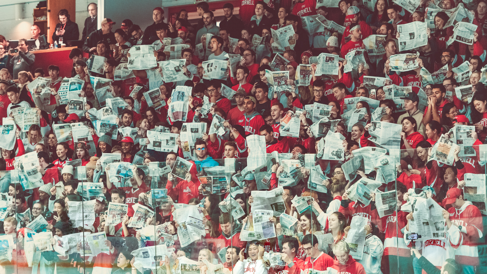 Fans reading newspapers at a Cornell hockey game