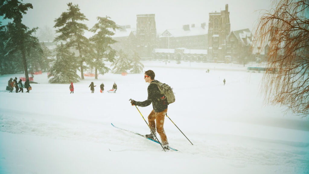 A student cross-country skiing on Libe Slope, above the War Memorial