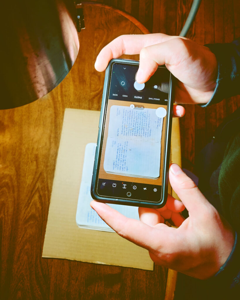 A man takes pictures of notebook pages with his smartphone.