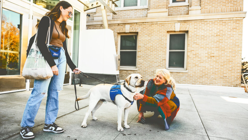 Zoe Weissbach and her guide dog puppy meet a visitor outside Stocking Hall