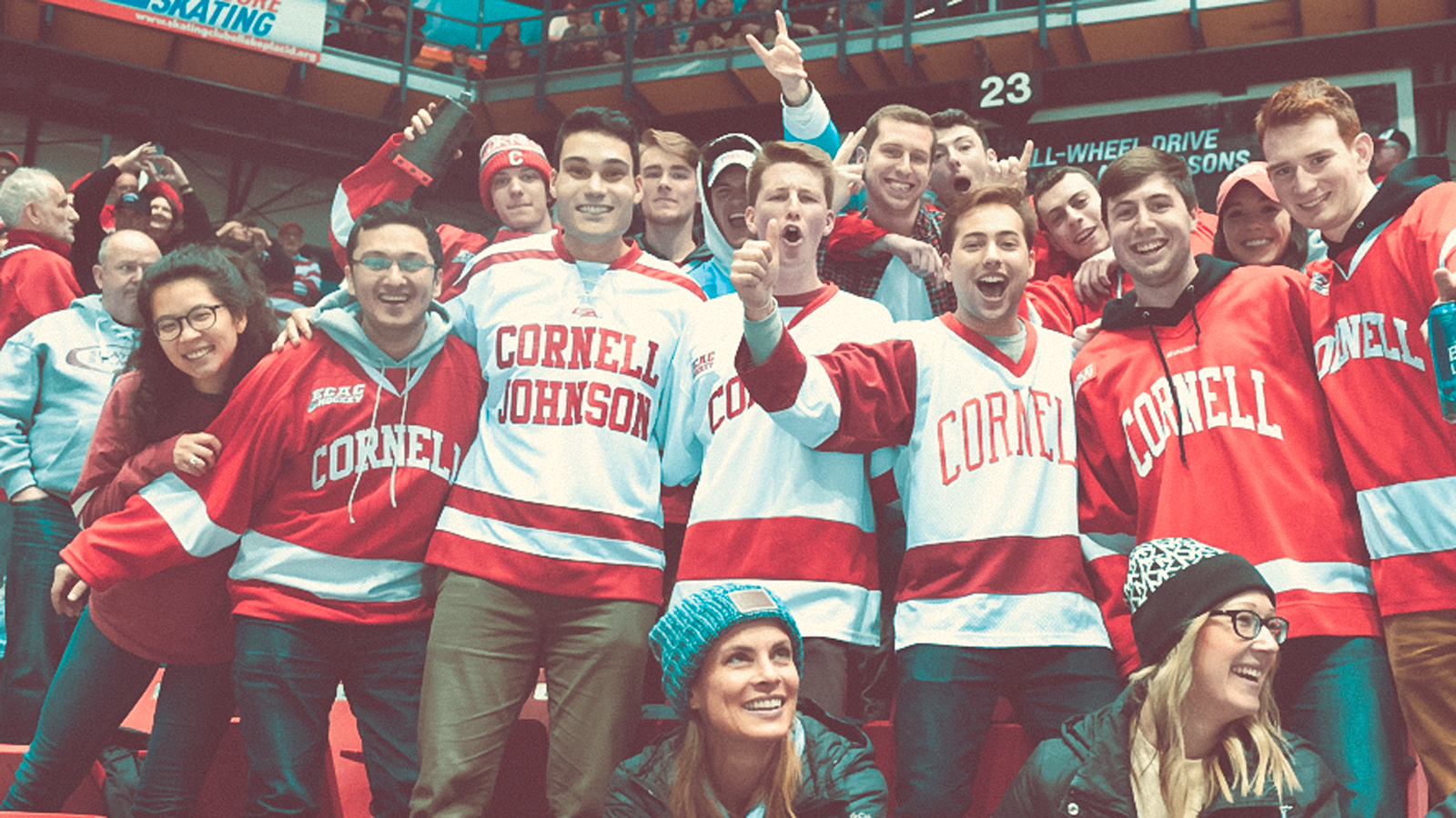 Cornell University hockey fans in the crowd for a game wearing red and white hockey jerseys.