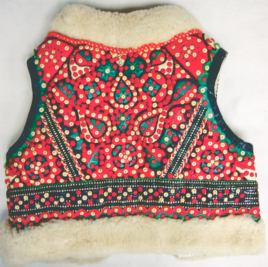 A 1930s child's vest from Yugoslavia with ornamental red and green beads and white fur trim.
