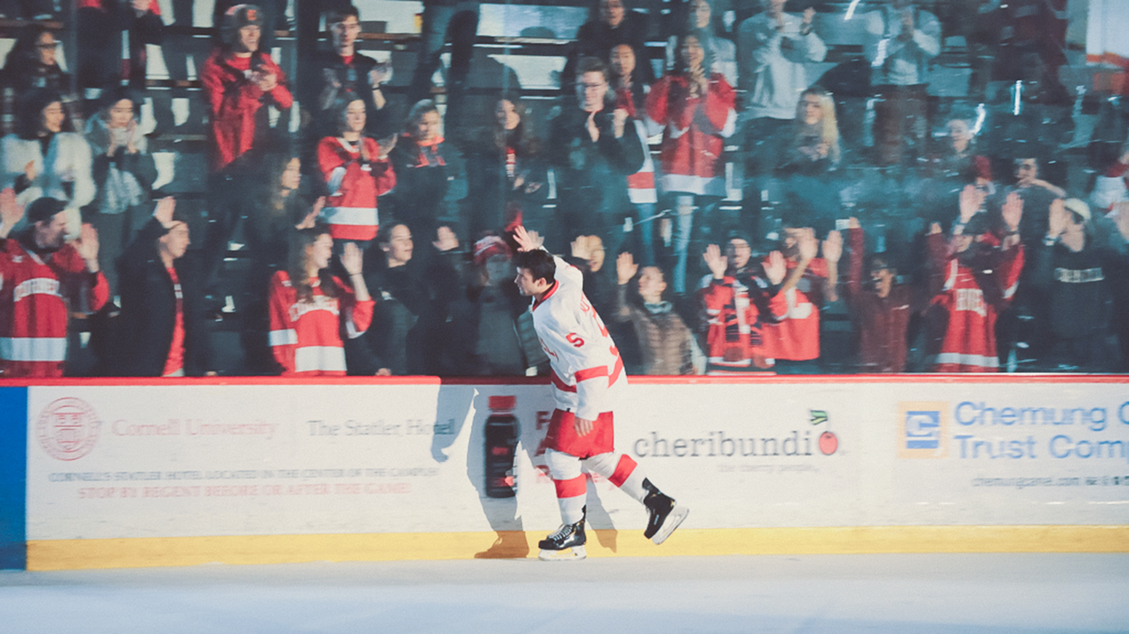 A Cornell men's ice hockey player greets fans at a game
