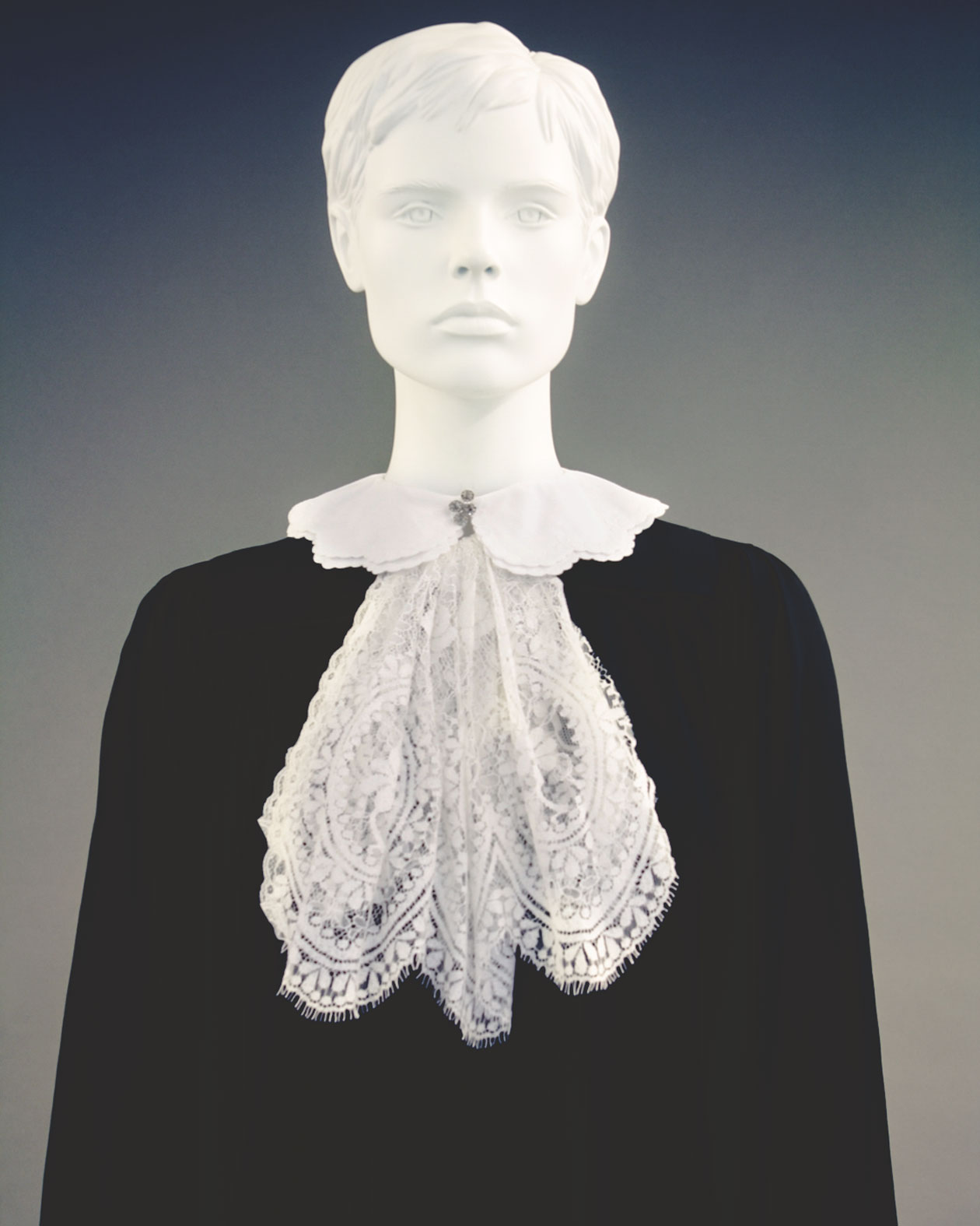 A white lace judicial collar shown on a mannequin wearing a black robe.