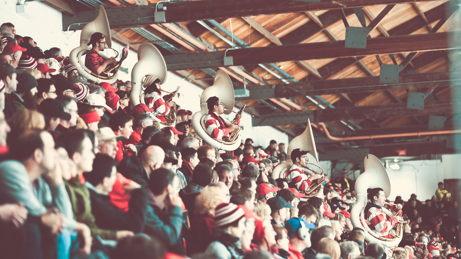 The crowd at a Cornell hockey game, including several members of a pep band playing their horns in the audience.