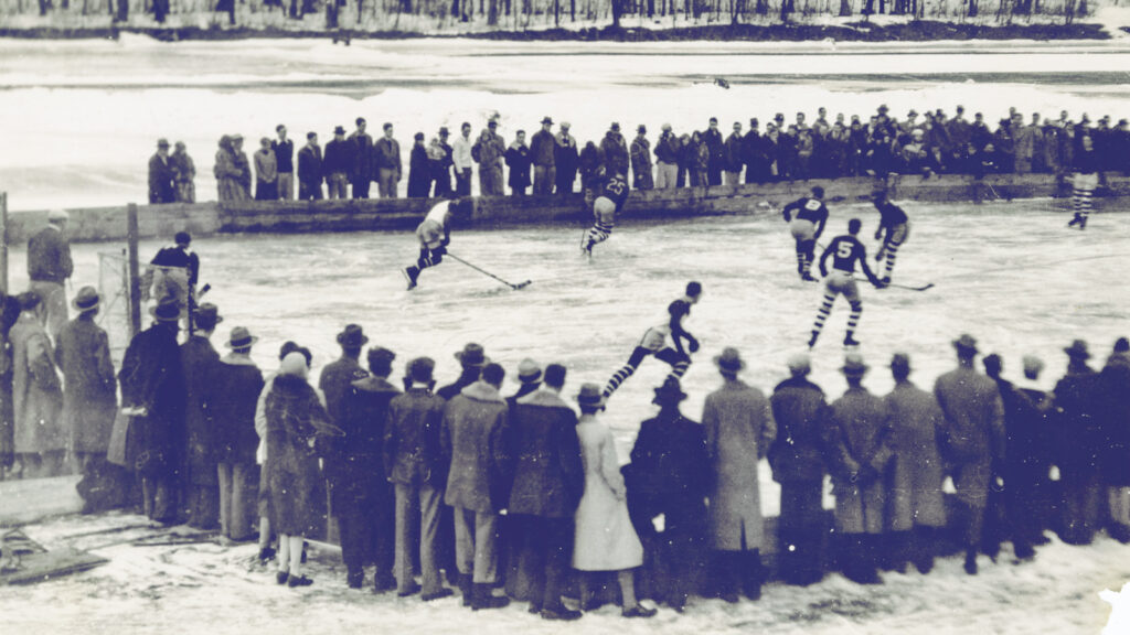An early hockey game on Beebe Lake, with spectators standing behind the low wooden rink walls