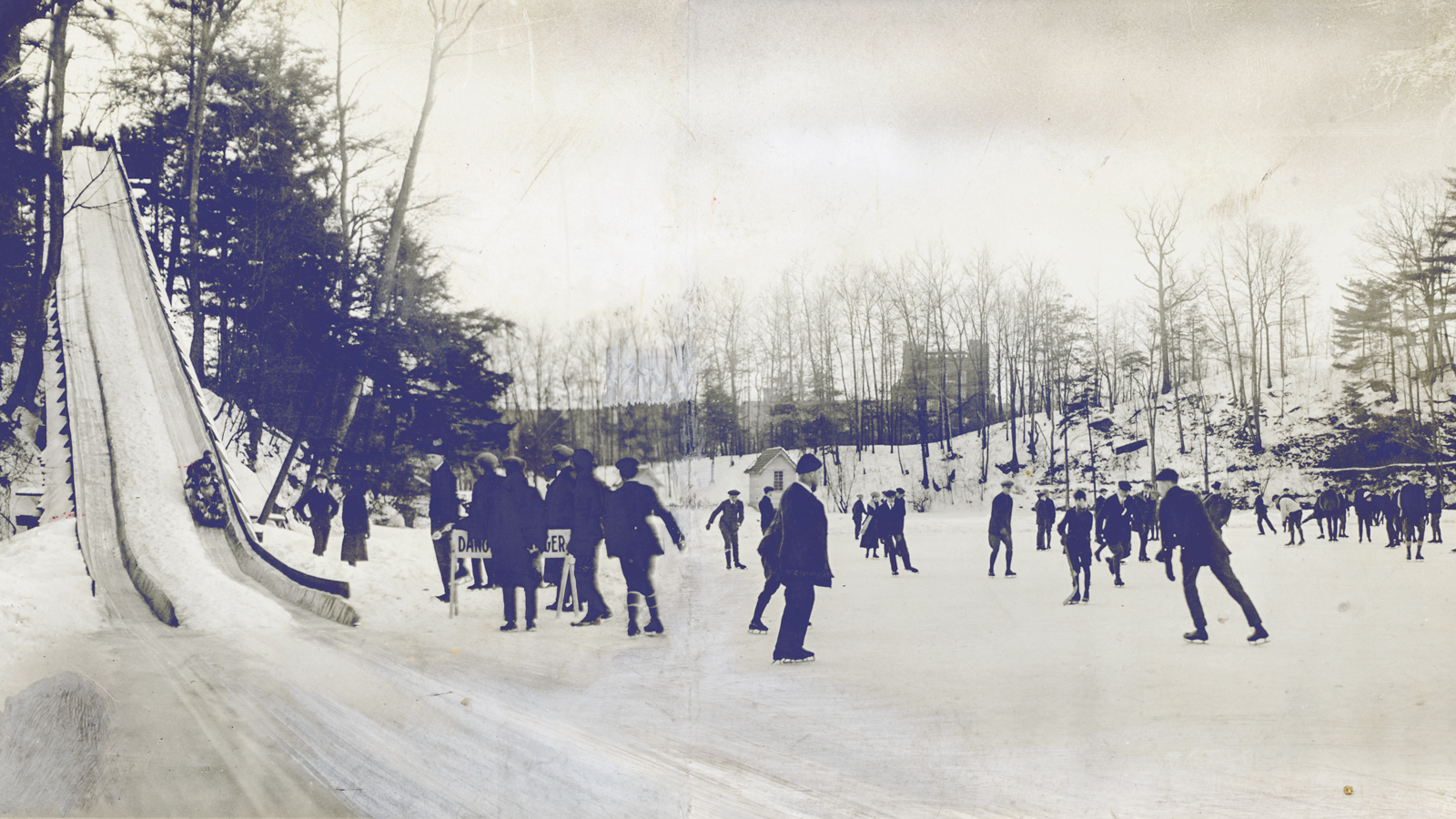 Wide view of Beebe Lake, showing the toboggan slide, ice skaters, and Risley Hall in the distance