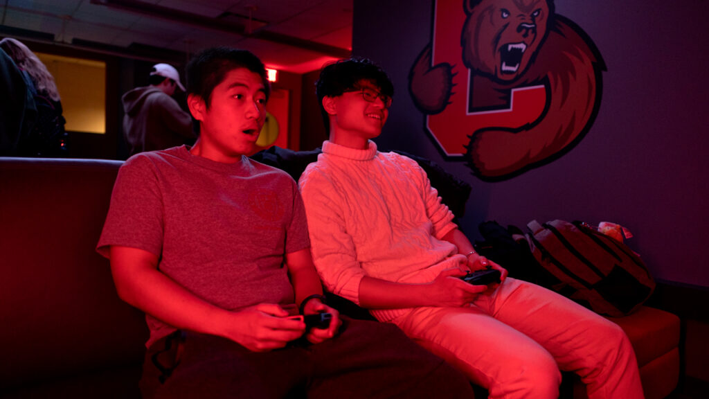 Two students bathed in red light in the eSports gaming lounge in Robert Purcell Community Center