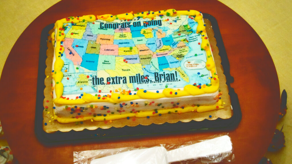 A cake with a map of the U.S. that says "Congrats on going the extra miles, Brian!"