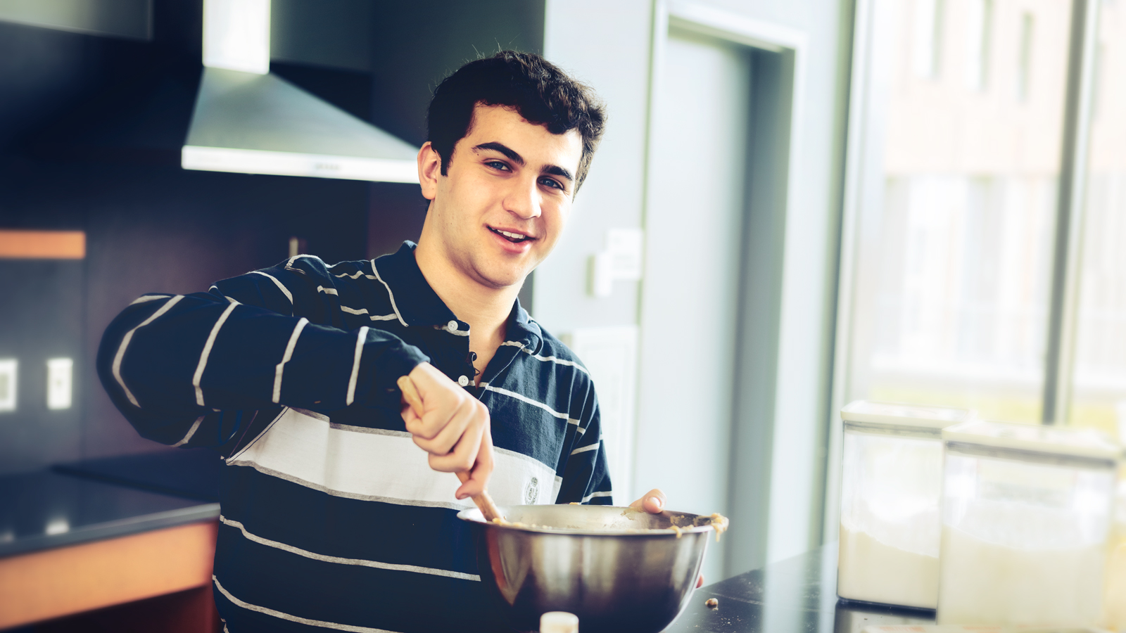 Matthew Merril stirs ingredients in a metal bowl in a kitchen