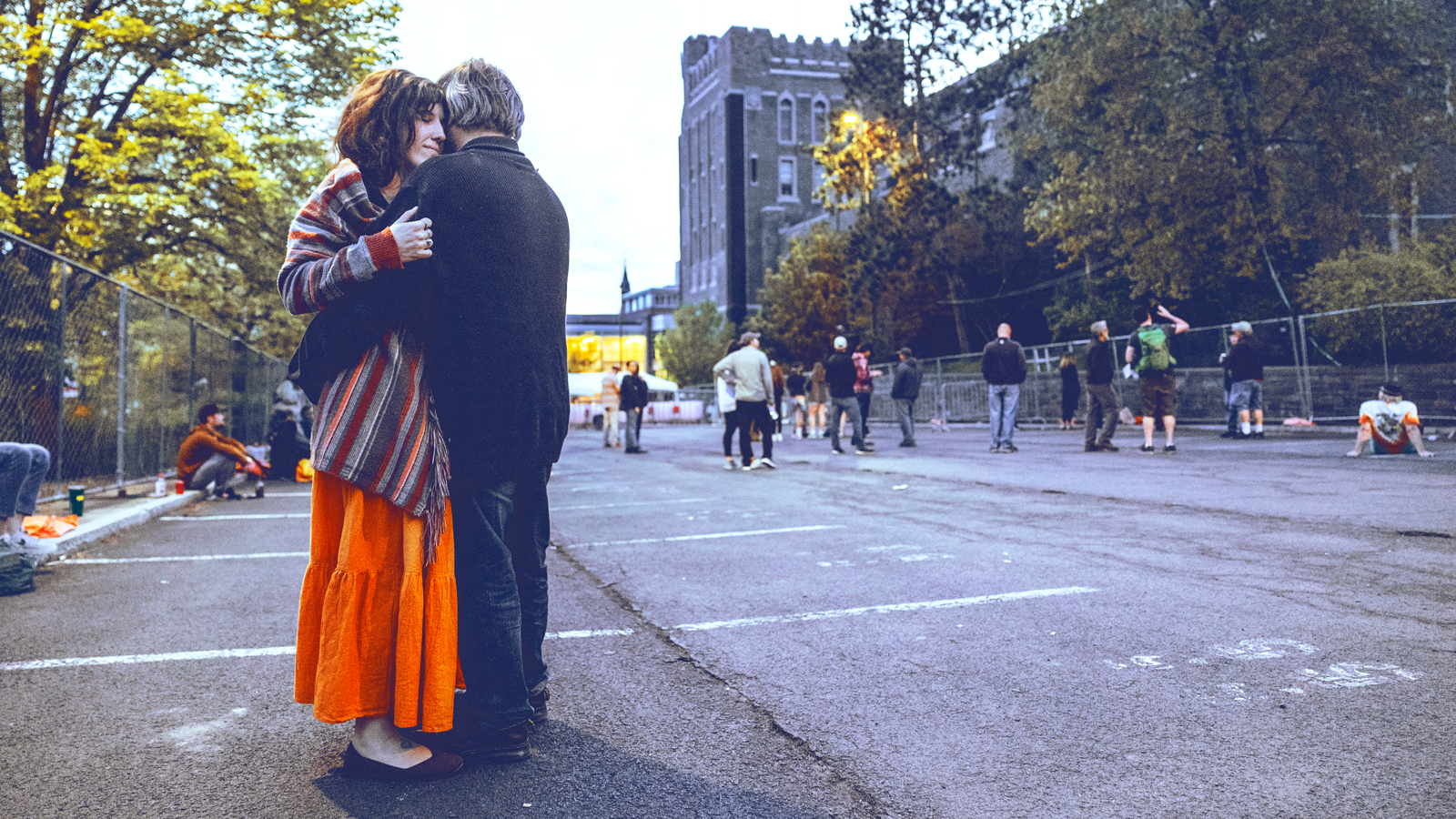 A man and woman embrace outside Barton Hall at Cornell University.