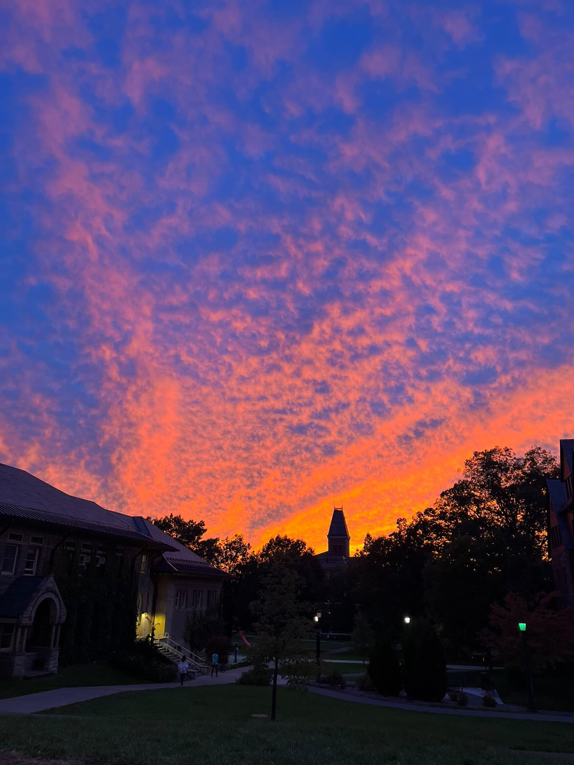 An orange sunset against a dark blue sky over the Cornell University campus.