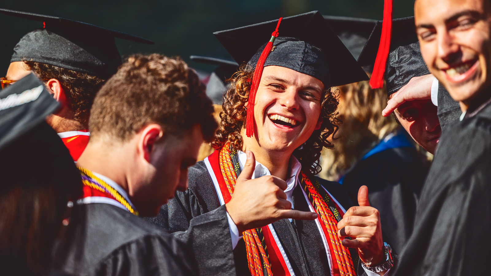 a graduate makes the "hang loose" shaka sign during Commencement 2023 ceremonies at Schoellkopf Stadium