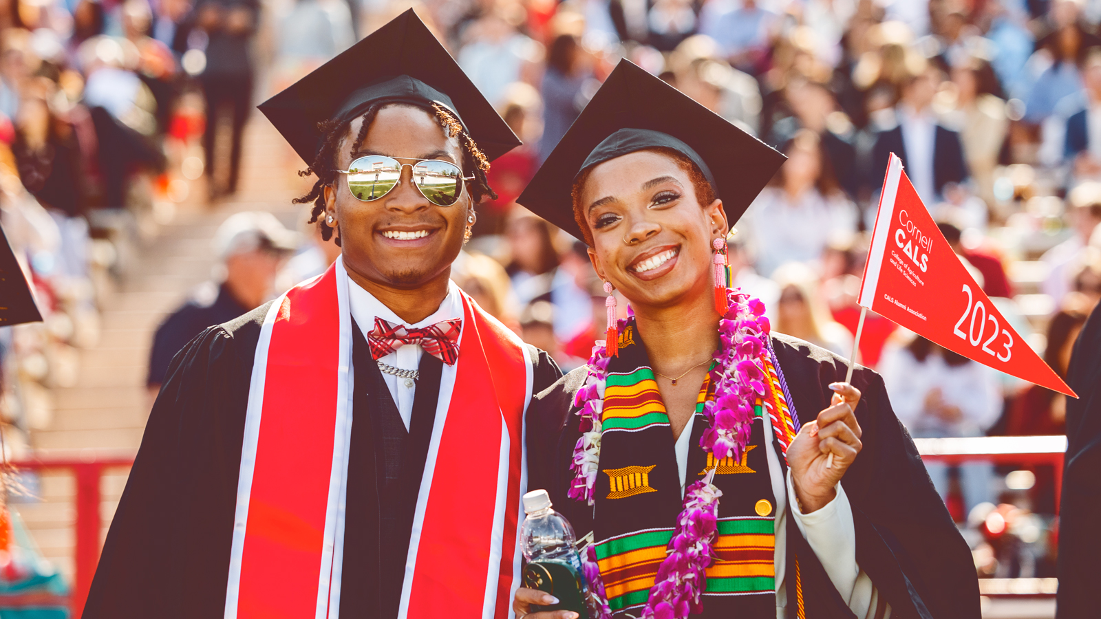 two graduates pose for a photo during Commencement 2023 at Schoellkopf Stadium
