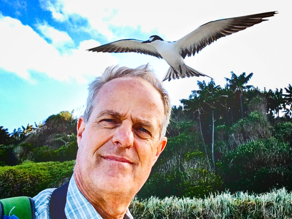 A man with a large white bird flying over his head