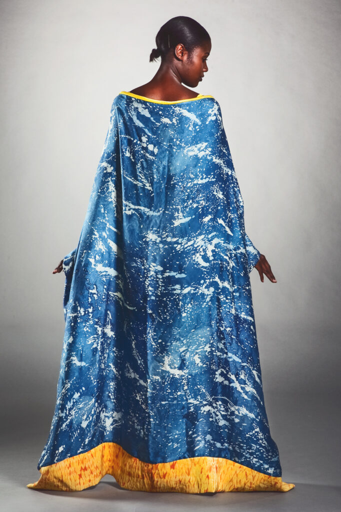 A woman wearing a blue and yellow cape naturally dyed with indigo and onion
