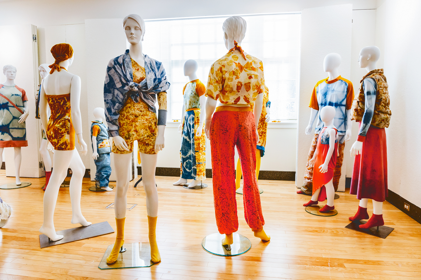 Mannequins arranged in a room wearing brightly colored clothing