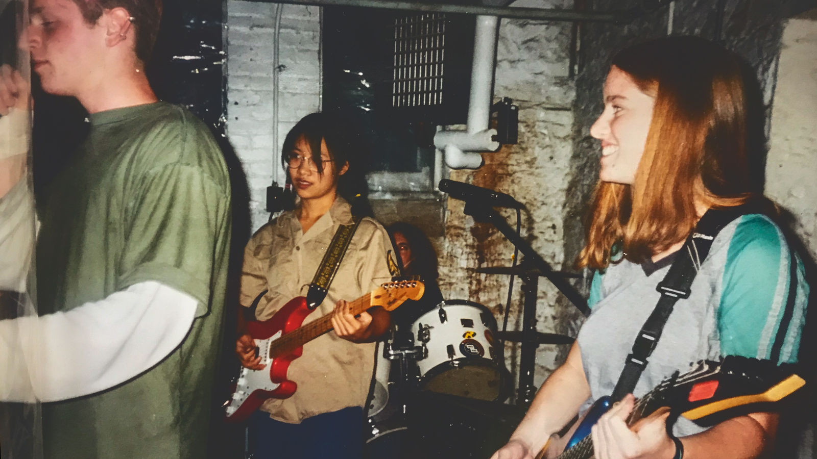 Two women and a man performing in a punk rock group.