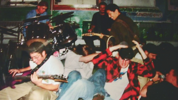 A blurry photo of several people playing rock music in Tjaden Hall