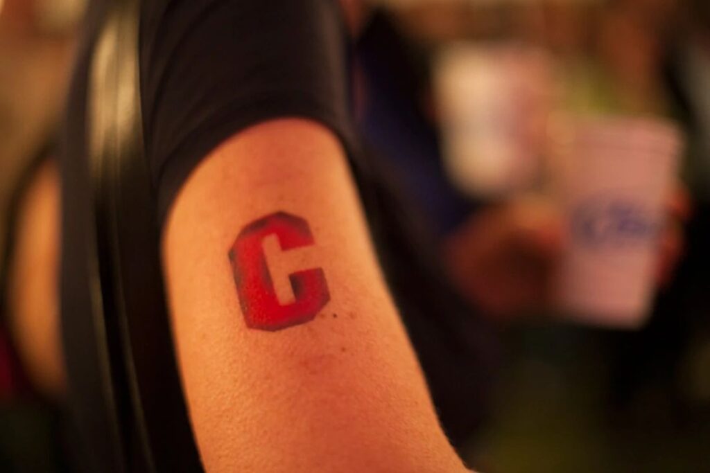 A red C tattoo on a person's upper arm.