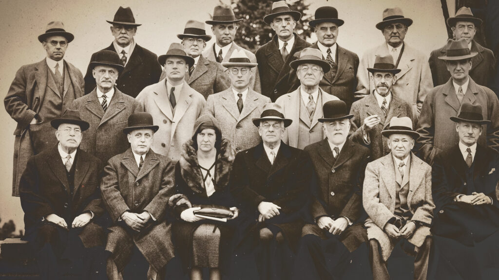 A group of men and one woman dressed in formal wear posing for a picture in 1931.