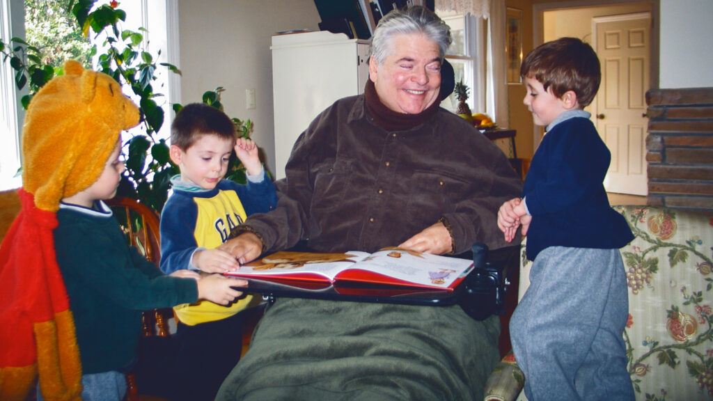 A man reads to three young boys.