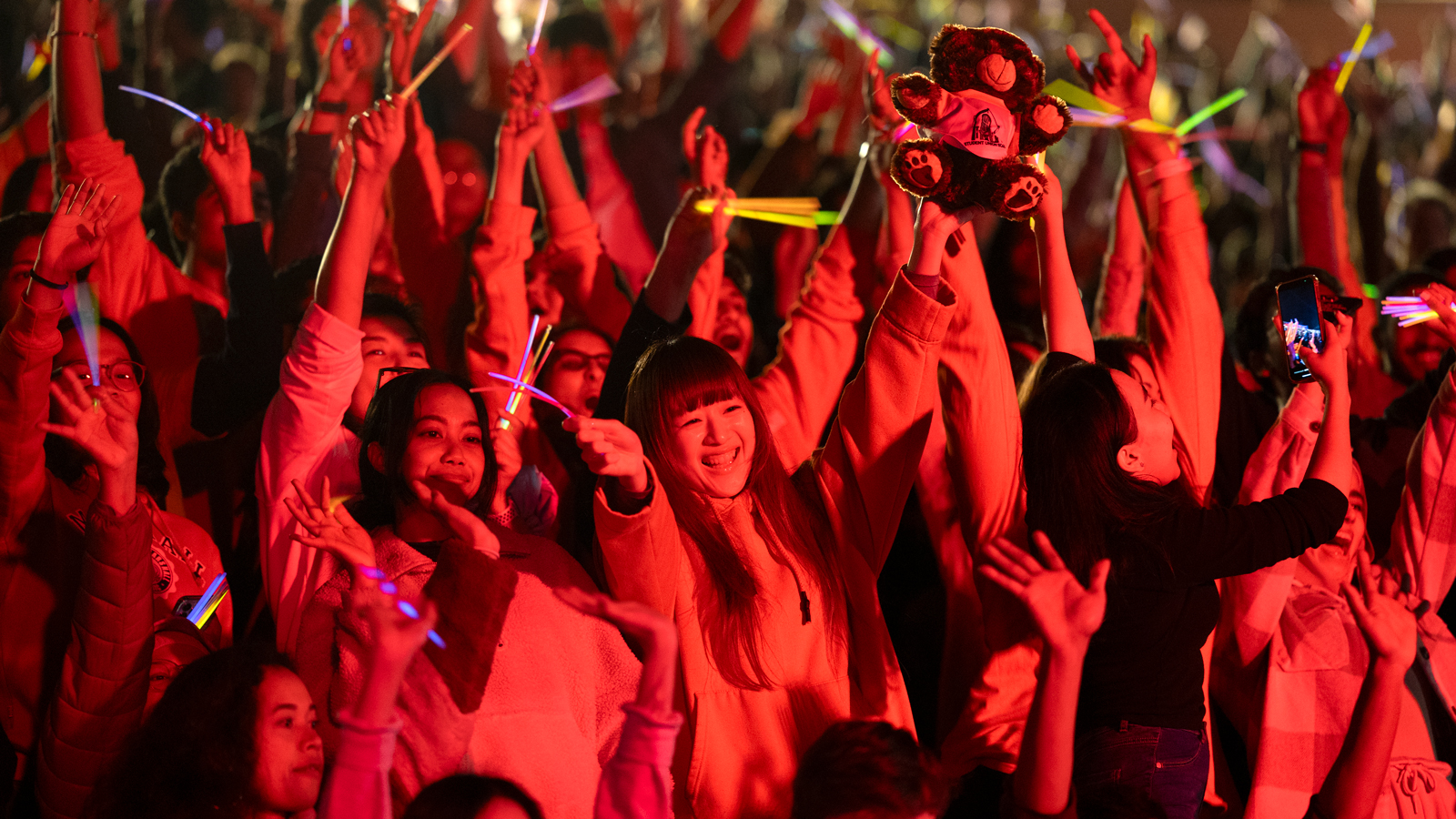 revelers are bathed in red light during the Homecoming fireworks and laser light show in Schoellkopf Stadium