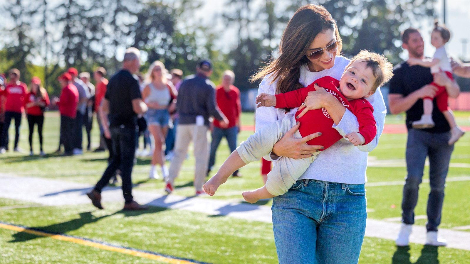A woman holds a small child at Schoellkopf Stadium before the Homecoming football game