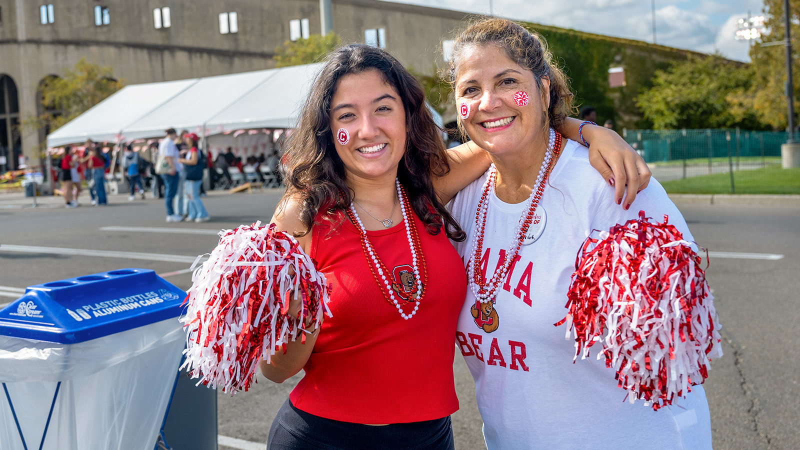 Two women pose for a photo, festooned in Big Red gear