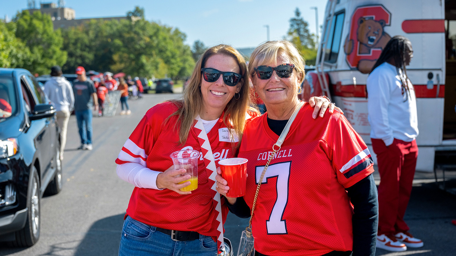 two attendees pose outside the Big Red Fan Festival at Homecoming